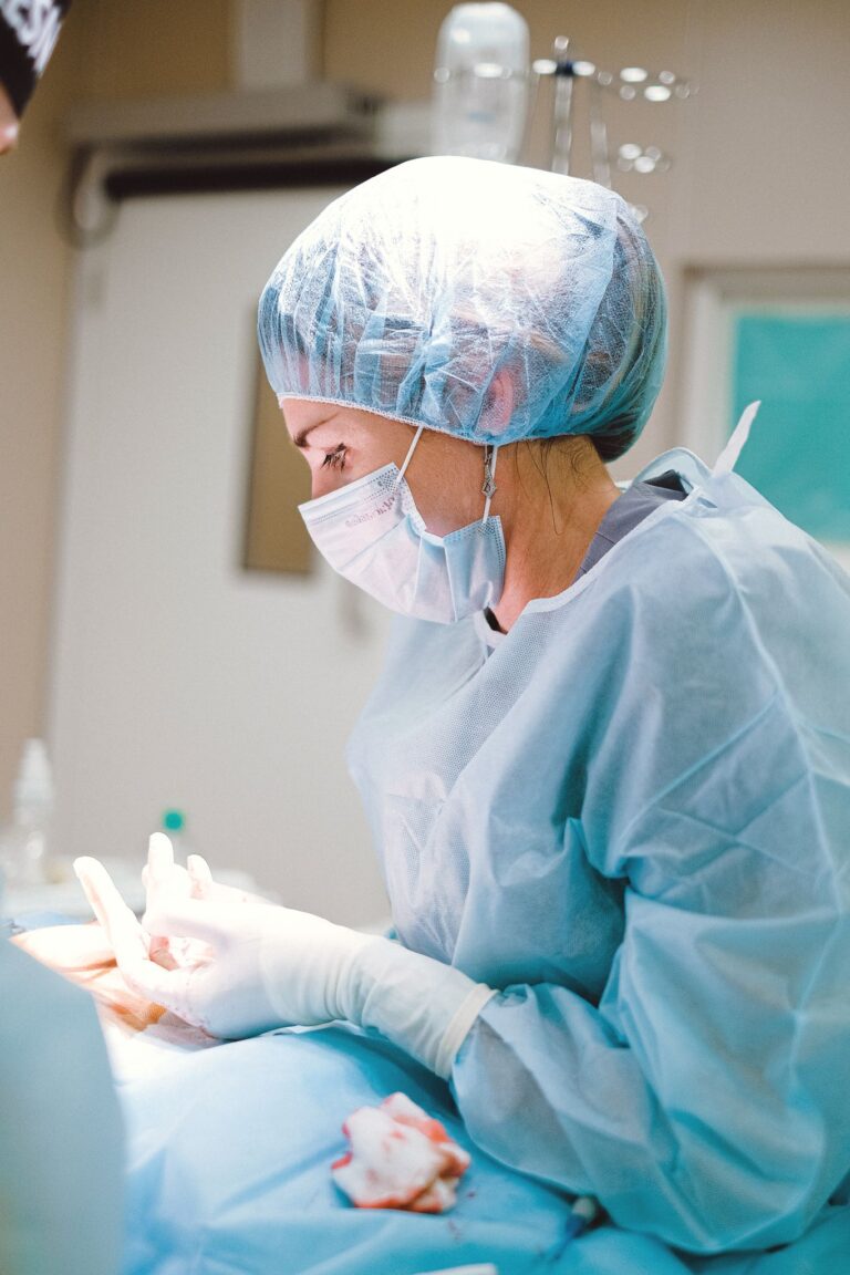 Female medical professional in surgical attire operating in a sterile room, focusing on patient care.