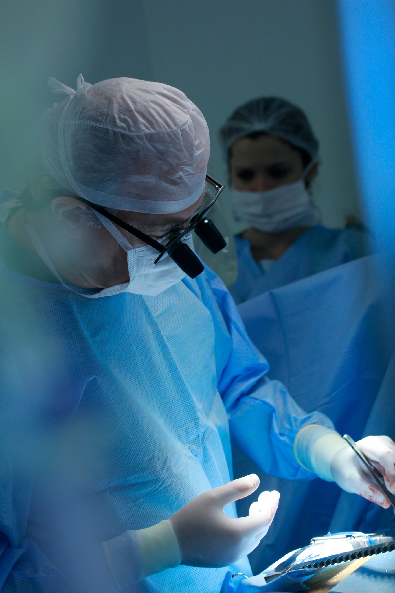 Surgeons working in a sterile operating room environment, wearing protective gear during a surgical procedure.